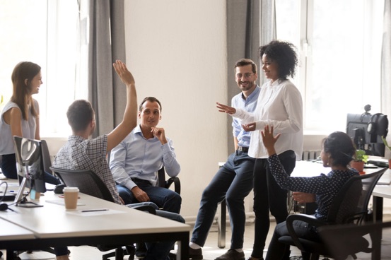 Diverse team in coworking space voting some colleagues agree raises hands. Positive black leader woman with creative group of businesspeople discussing sharing ideas together in office at meeting